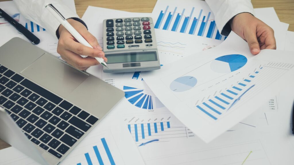 Travail sur un business plan avec des graphiques financiers, une calculatrice et un ordinateur portable.